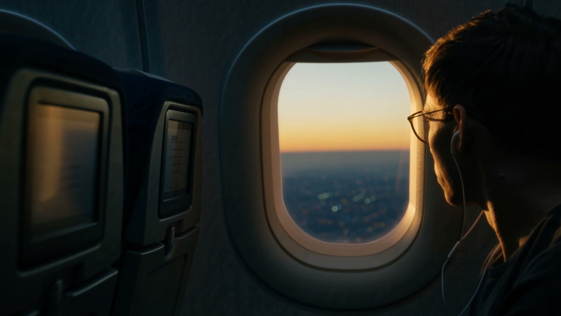 Un ragazzo guarda fuori dal finestrino di un aereo al tramonto
